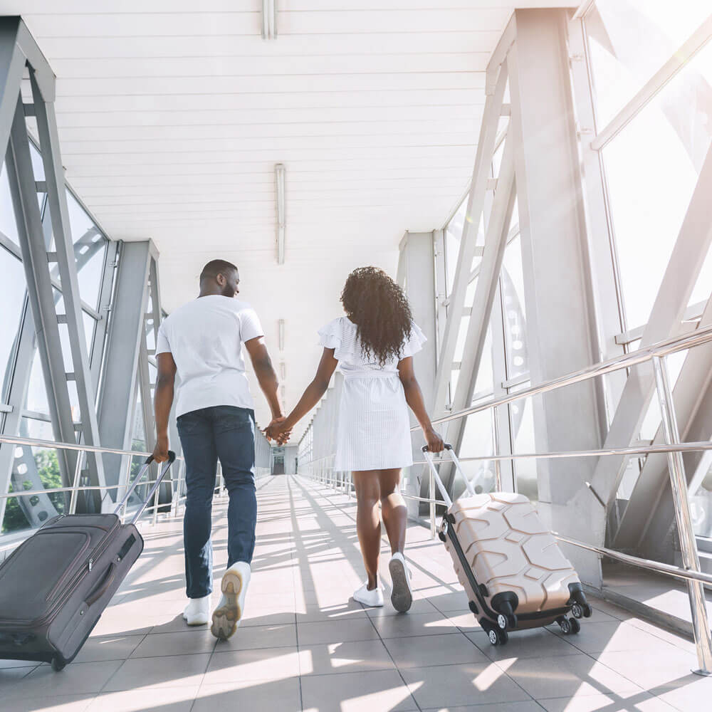 a couple walking their vacation luggage into an airport