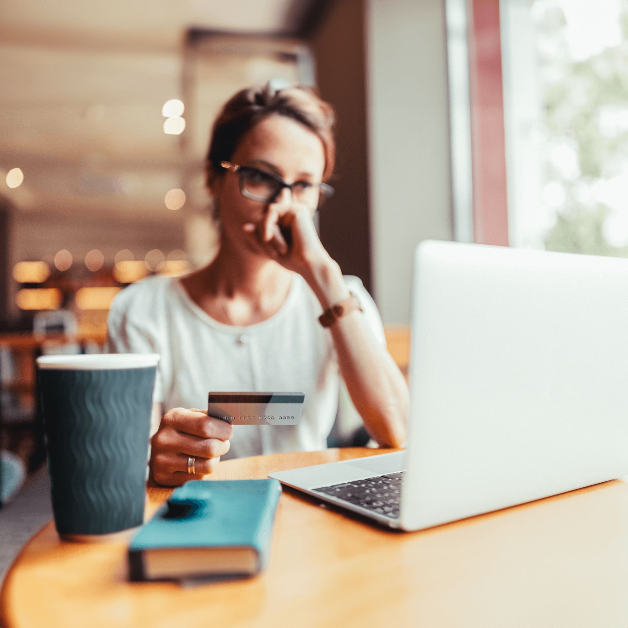 distressed woman holding a credit card reporting fraud on her laptop